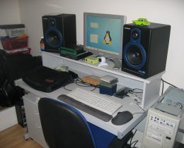 Postazione di home studio con rack, monitor da studio e strumentazione audio su una scrivania