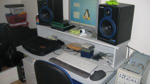 Postazione di home studio con rack, monitor da studio e strumentazione audio su una scrivania