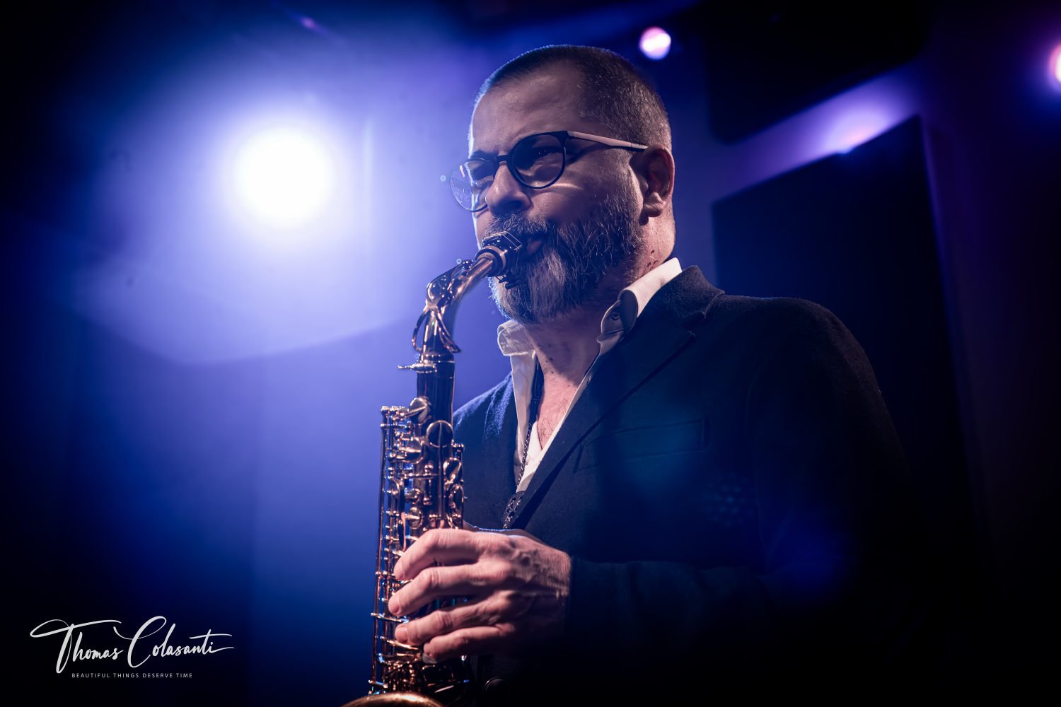 Rosario Giuliani suona il sassofono di profilo durante un concerto dal vivo, con un faretto visibile sullo sfondo