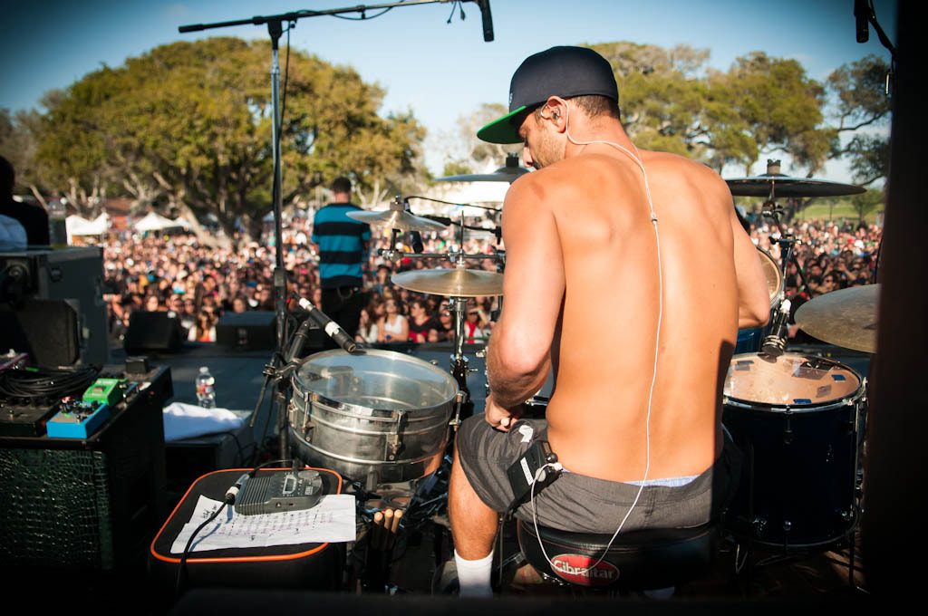 Batterista durante un concerto con in-ear monitor inseriti e cavo che scende verso il bodypack
