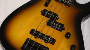 Primo piano del corpo di un basso elettrico sunburst con pickup split-coil e pickup a bobina singola sul ponte