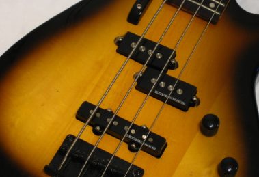 Primo piano del corpo di un basso elettrico sunburst con pickup split-coil e pickup a bobina singola sul ponte