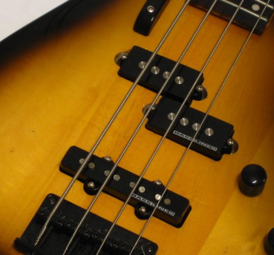 Primo piano del corpo di un basso elettrico sunburst con pickup split-coil e pickup a bobina singola sul ponte