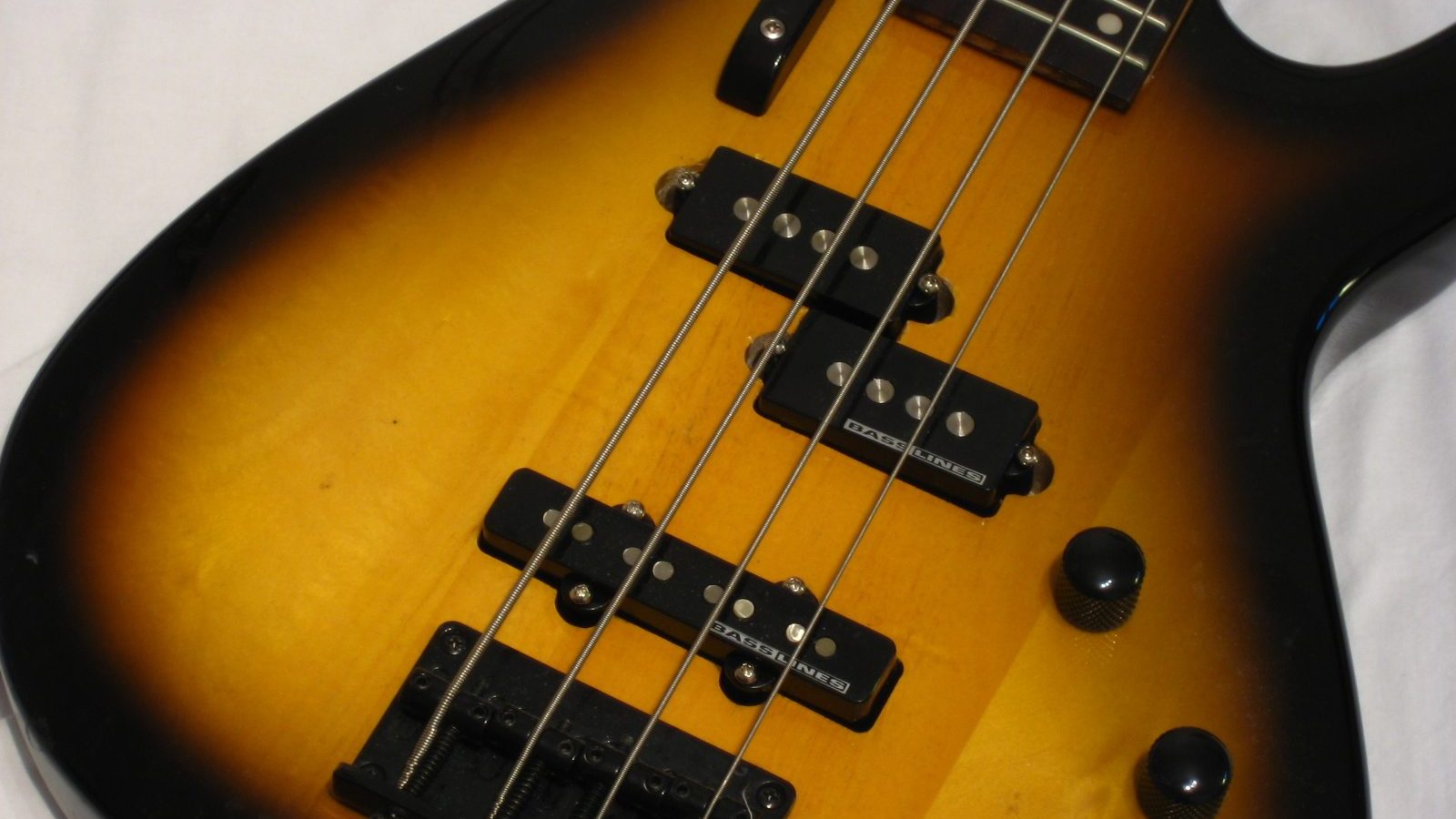 Primo piano del corpo di un basso elettrico sunburst con pickup split-coil e pickup a bobina singola sul ponte