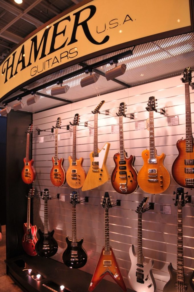 Chitarre Hamer appese allo stand del marchio durante una fiera di strumenti musicali