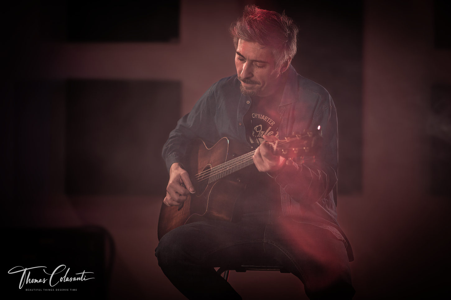 Marco Galiero seduto mentre suona una chitarra acustica nello studio