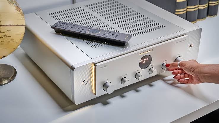 Amplificatore Marantz in finitura argento e oro, ripreso di tre quarti con il telecomando appoggiato sul coperchio