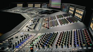 Console analogica SSL Odyssey da 48 canali vista di tre quarti, con le strisce di canale e la sezione centrale illuminate