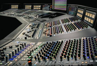 Console analogica SSL Odyssey da 48 canali vista di tre quarti, con le strisce di canale e la sezione centrale illuminate