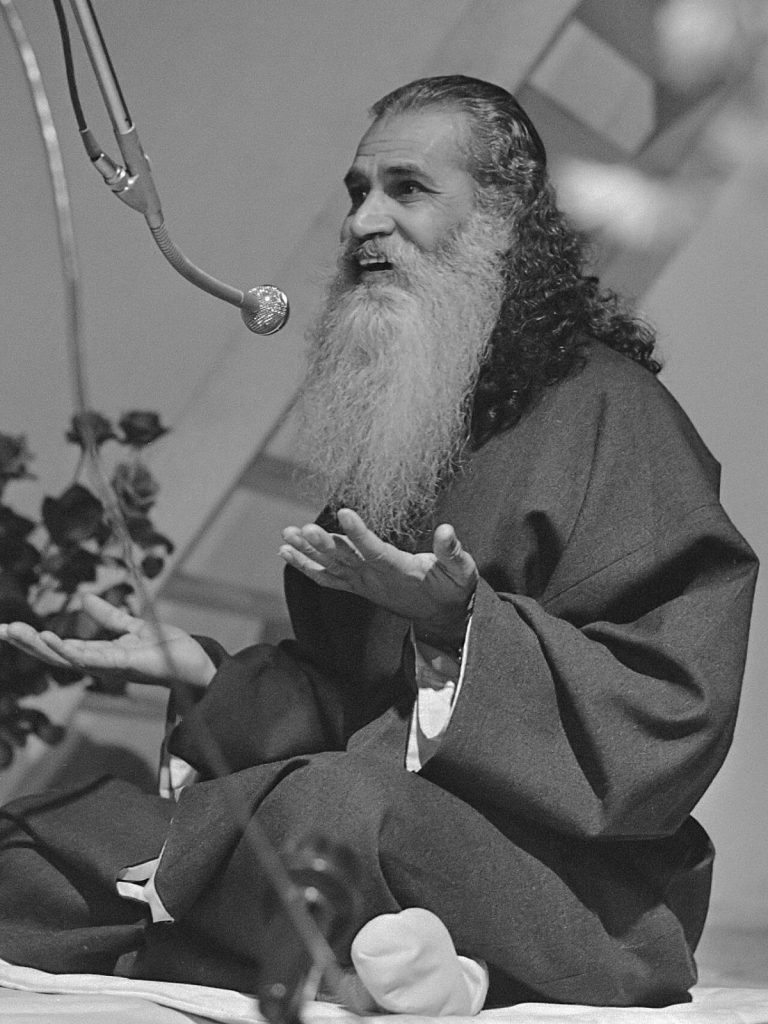 Swami Satchidananda parla al microfono al Kosmos di Amsterdam nell'ottobre 1970, in abito monastico e con la barba bianca